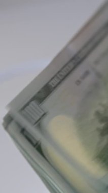 Para sayma makinesinde 100 dolarlık banknotlar saydı. Cihazların dönme mekanizması yaklaşıyor. Arkaplan bulanık. Dikey video