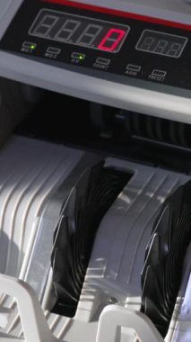 Elektronik nakit sayma makinesi elli avro banknot sayıyor. Rakamlar arka plandaki ekranda bulanık bir şekilde hızla değişiyor. Kapatın. Dikey video