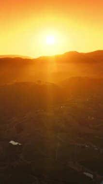 Güzel parlak güneş dağların arkasında saklanıyor. Napa, California, ABD 'nin batan güneşinin huzurlu manzarası. Hava görüntüsü. Dikey video