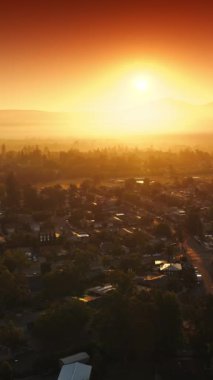 Napa, California, ABD üzerinde turuncu parlak gökyüzü. İHA, batan güneş ışınlarıyla rahat evlerin üzerinde uçuyor. Dikey video