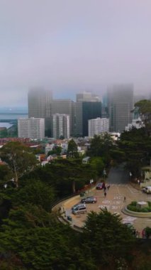 San Francisco rıhtımının çağdaş güzel mimarisi. Kalın sisli güzel evler ve gökdelenler. Köprü arka planda. Dikey video