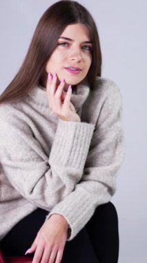 İçerideki koltukta oturan uzun saçlı güzel bayan. Çekici kadın başını eğip baktı. Beyaz zemin. Dikey video