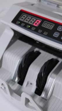 Banka ekipmanlarındaki 100 dolarlık banknotları sayıyorum. Beyaz para sayma makinesi çalışıyor. Yüksek açı. Dikey video