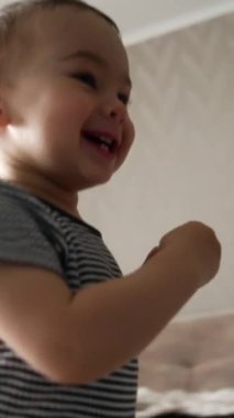 Gülümseyen mutlu çocuk odanın önünden geçiyor. Çocuk duvara doğru koşuyor ve üzerine bir şey yapıştırıyor. Düşük açı. Dikey video
