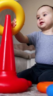 Güzel beyaz çocuk piramit inşa ediyor. Mutlu erkek bebek evde oynuyor. Kara kedi arka planda. Düşük açı. Dikey video