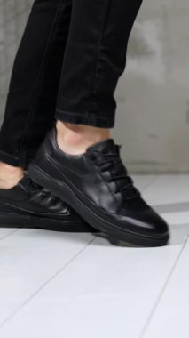 Siyah kotlu ve deri ayakkabılı, ay yürüyüşü yapan tanınmamış bir adam. Stüdyoda şık erkek ayakkabıları gösterisi. Dikey video