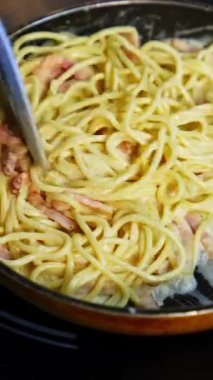 Lezzetli soslu pastırmalı makarna. Kızartma tavasında lezzetli yemekler pişirmek. Şef bir restoranda makarna pişiriyor. Yemek malzemesi. Mutfakta yemek pişirmek. Gurme için pişirilmiş. Dikey video