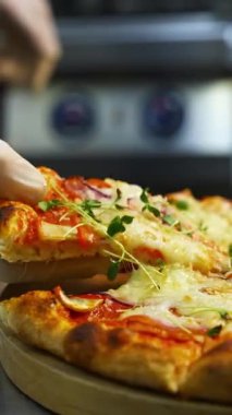 Pizzayı elimle alıyorum. Sıcak, lezzetli pizzalar hazır. Tahta üzerinde pizza. Taze yeşil lahanalı lezzetli pizza. Yakın plan. Dikey video