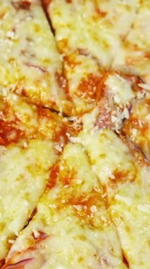 Hazır pizza peynirle serpiştirilmiştir. Eritilmiş peynir ve diğer malzemelerle iyi pişmiş pizza. Lezzetli çerez. Yakın plan. Üst Manzara. Dikey video