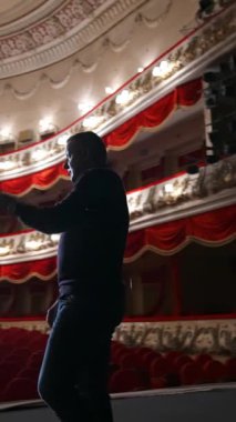 Klasik tiyatro arka planında sahnedeki adam. Gösteriden önce prova. Aktör boş oditoryumla konuşuyor. Olay yerinden görüntü. Dikey video