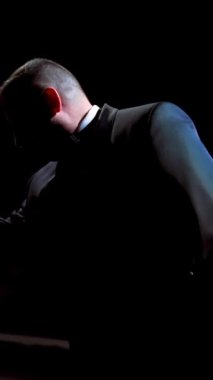 Aktör tiyatro sahnesinde bir gösteri yapıyor. Siyah takım elbiseli bir adam şapkasını giydi ve karanlıkta spot ışıklarının karşısında dans etmeye başladı. Dikey video