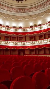 Opera binasının konser salonundaki boş koltuklar. Kırmızı sandalyeli güzel bir tiyatro salonu. Klasik tiyatroda üç kat insan yok. Dikey video