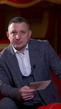 Kostümlü adam senaryo okuyor. Bir aktörün kırmızı sandalyeler arasında boş tiyatroda prova yaptığı orta boy bir sahne. Oyunculuk yaşam tarzı. Dikey video