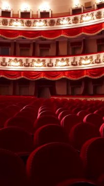 Kapalı alanda kırmızı renkli güzel bir tiyatro. Opera binasında boş koltukları olan geniş bir salon. Klasik tiyatroda boş sandalyeli üç kat vardır. Dikey video