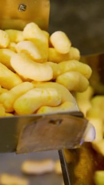 Taşıyıcı bantta besleyici mısır ürünleri var. Fabrikada tatlı abur cubur imalatı. Kapatın. Dikey video