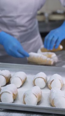 Yiyecek fabrikasında nefis tatlı paketleri var. Şekerleme işçisi plastik kutulara biraz cannoli keki koyar. Kapatın. Dikey video