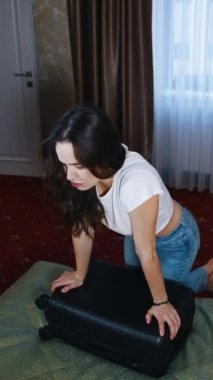 Bavulunu topladıktan sonra yorgun bir kadın. Genç bayan bavullarını toplayıp rahat bir otel odasında yatağa düşüyor. Seyahatin sonu. Dikey video