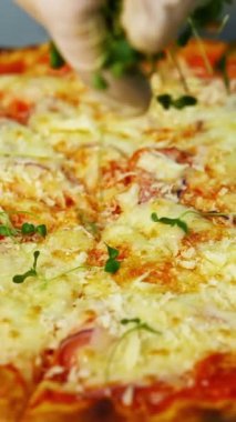 Cook hazır pizzayı süslüyor. Şefin eli eldivenli. Restoranda fırında pişmiş pizzaya taze yeşil lahanalar serpiştiriyor. Yakın plan. Dikey video