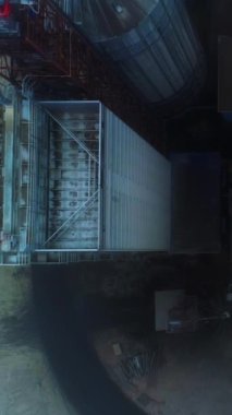 Boyutsal asansör yapıları ve binaların üzerinde uçuyorlar. Sisli bir günde modern tarım fabrikalarının dev tankları. Üst Manzara. Dikey video