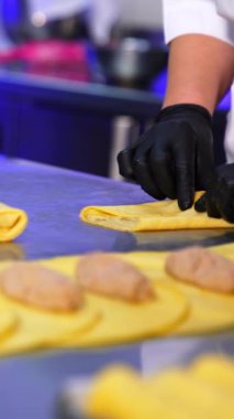 Lezzetli sarı krepler kızarmış etle dolduruluyor. Modern restoranda yarı pişmiş gıda üretiyor. Kapatın. Ön planda bulanıklık. Dikey video