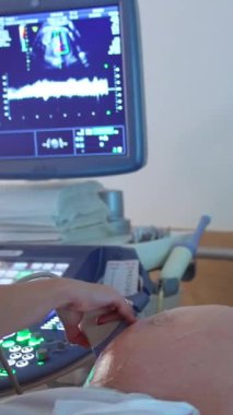 Hamile kadın için ultrason testi. Maskeli kadın ultrasonik muayene için kanepede yatıyor. Dikey video