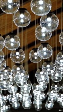 Işıl ışıl lambaların içi. Modern tavan aydınlatmasının bulanık görüntüsü. Ampul topları içeride asılı. Dikey video