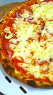 Bol peynirli, pastırmalı ve domatesli leziz bir pizza. Şef yeni hazırlanmış pizzayı tahta tahtaya koyar. Dikey video