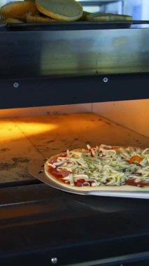 Bir kafedeki Tahta Masa 'da Taze Hazırlanmış Pizza. Modern bir restoranın arka planında iştah açıcı sıcak pizza. Dikey video