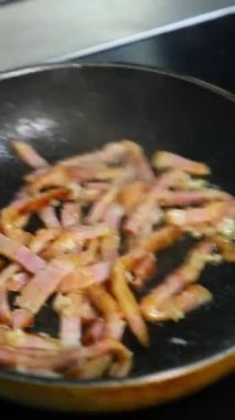 Tavada kızarmış pastırma parçaları. Lezzetli pastırma parçaları sıcak tavada kızartılır. Sağlıksız yiyecekler. Dikey video