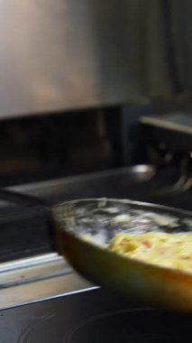 Pastırmalı spagetti, tavada bitki ve yumurta. Şef kızartma tavasında carbonara yapıyor. Lezzetli yemekler. Dikey video