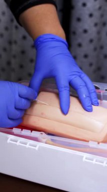 Eldivenli eller iğne yaparken iğne batırıyor. Simülasyon tıbbi eğitim modeli. Tıbbi prosedür konsepti, simülasyon tıp eğitimi. Dikey video