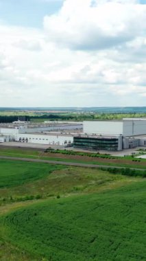 Saha gerisinde modern fabrika. Güzel gökyüzü altında, yeşil doğa arasındaki devasa sanayi bölgesi. Bir imalatın ön görüntüsü. Dikey video