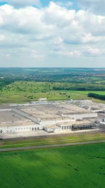 Şehrin dışında büyük bir fabrika. Yeşil tarlalarda ve ormanlarda endüstriyel fabrikalar. Doğa arasındaki modern sanayi bölgesine yukarıdan bakın. Hava görüntüsü. Dikey video