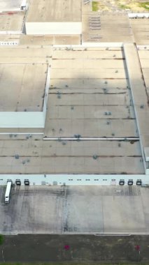 Endüstriyel fabrikanın çatıları. Birçok bina birlikte inşa edildi ve büyük modern bir fabrikanın otoparkları yapıldı. Üst Manzara. Dikey video