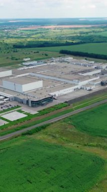 Yeşil alanda büyük bir sanayi bölgesi. Yazın etrafı güzel manzaralarla çevrili bir fabrika. Hava görüntüsü. Kamera geri gidiyor. Dikey video