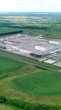 Kırsal kesimde modern bir fabrika. Yeşil doğa arka planında yenilikçi endüstriyel bitki kompleksi. Tarlalarda sanayi bölgesi. Hava görüntüsü. Dikey video