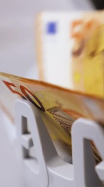 Modern bankacılık faaliyetleri. Sayılırken Avro banknotları. Bir veznedarın eli sayaç makinesinden para alıyor. Yakın plan. Dikey video