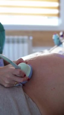 Koca göbekli hamile kadın doğum kontrolünde şu an. Doktor gelecekteki anne için ultrason taraması yapıyor. Dikey video