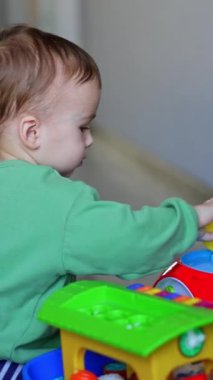 Beyaz bir bebek yerde bir oyuncakla oynuyor. Sakin çocuk oyuncak ağzına bastırıyor ama tekrar ortaya çıkıyor. Arkaplanda Noel ağacı.