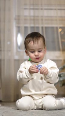 Tatlı beyaz çocuk, elinde emzik tutarak yerde oturuyor. Bebek kameraya doğru sürünüyor ve sonra Noel ağacına dönüyor..