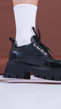 Traktör tabanlı büyük deri ayakkabılar. Model, beyaz çoraplara giyilen şık ayakkabıları gösteriyor. Kapat..