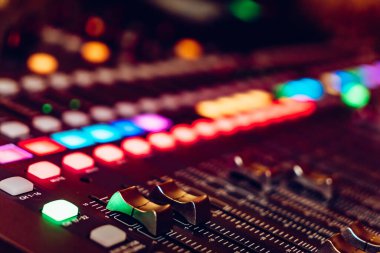 Ses karıştırma konsolunun renkli düğmeler ve düğmelerle yakın plan görüntüsü. Canlı ışıklandırılmış düğmeler ve düğmeler içeren bir ses karıştırma konsolunun ayrıntılı görünümü.