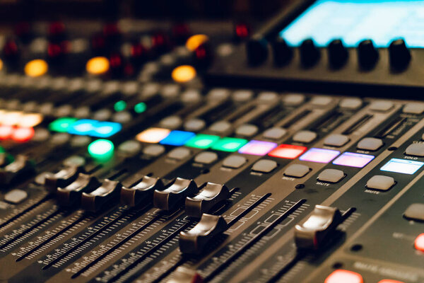 Панель управления с цветными огнями во время сеанса микширования звука. Подробный обзор звуковой микшерной консоли с красочными кнопками и выцветателями во время живого выступления.