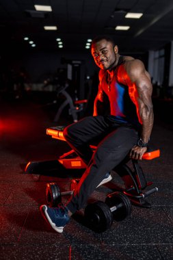 Geceleri loş bir spor salonunda yedek kulübesinde dinlenen güçlü bir sporcu. Bir sporcu spor malzemelerinin arasında spor yaptıktan sonra bankta dinlenir..