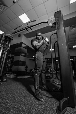 Spor salonundaki spor aletlerini antrenman için kullanan bir sporcu. Vücut geliştiren biri modern bir spor salonunda bir makine üzerinde egzersiz yapar..