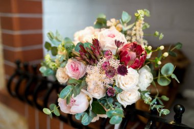 Şömine rafında gül ve yeşillik olan güzel bir çiçek buketi. Bir şömine rafına yerleştirilmiş canlı bir buket gül ve çeşitli çiçekler..