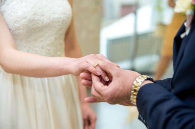 Çiftler tören sırasında parlak bir mekanda alyanslarını değiş tokuş ederler. Bir damat tören sırasında gelinin parmağına bir alyans takar..