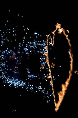 Ateş sanatçısı karanlık gece gökyüzünde göz kamaştırıcı kıvılcımlar yaratıyor. Bir ateş sanatçısı ustalıkla alevleri yakar ve karanlık bir zemine kıvılcımlar saçar..