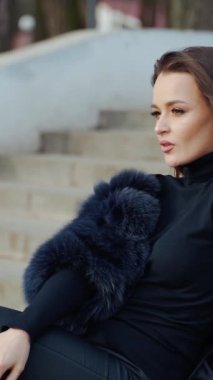 Koyu renk kürk giyen seksi esmer kadın kameraya bakarken yüzüne yakın duruyor. Moda videosu. Dikey video