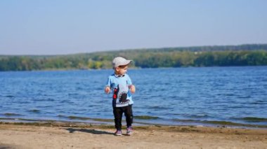 Güneşli nehir sahillerinde eğleniyoruz. Kumsalda oynayan küçük çocuk..